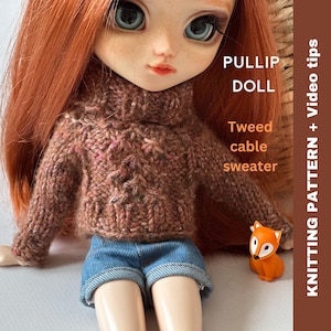May include: A brown tweed cable knit sweater for a doll. The sweater has a turtleneck and is worn by a doll with red hair. The doll is sitting on a white surface with a small orange fox figurine. The text on the image reads "PULLIP DOLL Tweed cable sweater" and "KNITTING PATTERN + Video tips".