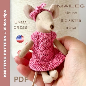 May include: A handmade Maileg Mouse Big Sister doll, approximately 5 inches (13 cm) tall, wearing a pink knitted dress and headband. The doll has beige fabric ears and limbs. The image includes text that says "EMMA DRESS" and "KNITTING PATTERN + Video tips".