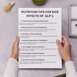 May include: A white paper titled "NUTRITION TIPS FOR SIDE EFFECTS OF GLP-1" is held by hands. The paper lists seven tips, including eating slowly to reduce bloating and avoiding trigger foods for heartburn. A matcha whisk and a green apple are visible.