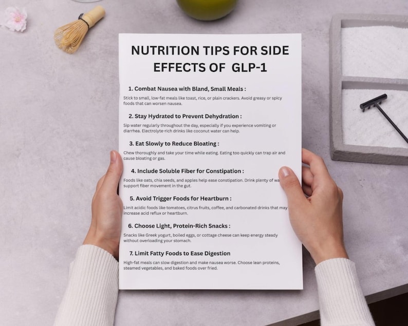 May include: A white paper titled "NUTRITION TIPS FOR SIDE EFFECTS OF GLP-1" is held by hands. The paper lists seven tips, including eating slowly to reduce bloating and avoiding trigger foods for heartburn. A matcha whisk and a green apple are visible.