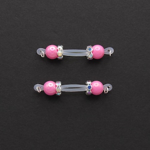 May include: Two pairs of pink bead jewelry connectors. Each connector has a pink bead on each end, connected by a clear, flexible band. The beads are accented with iridescent rhinestones and silver-colored metal loops.
