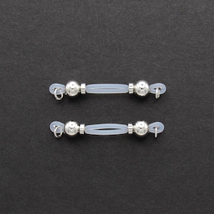 May include: Two pairs of silver eyeglass retainers. Each retainer features a silver ball on each end, connected by a clear, flexible tube. The retainers have small loops for attaching to glasses and are set against a dark background.