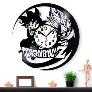 Könnte beinhalten: Schwarze Vinyl-Schallplattenuhr mit den Dragon Ball Z-Charakteren Goku und Vegeta. Das Zifferblatt ist weiß mit schwarzen Zahlen und Zeigern. Die Worte "DRAGON BALL Z" sind darunter abgebildet.