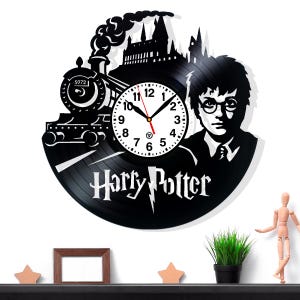 May include: Black vinyl record clock featuring a train, Hogwarts castle, and a silhouette of Harry Potter. The clock face is white with black numbers and hands. The words "Harry Potter" are displayed below the clock face.