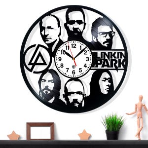 May include: Black vinyl record clock featuring portraits of Linkin Park band members. The clock face has a white background with black numbers and hands. The band's name is displayed in a stylized font. The clock is mounted on a white wall.