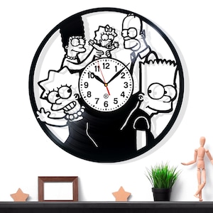 Può includere: Orologio in vinile in bianco e nero con la famiglia Simpson. Il quadrante dell'orologio è bianco con numeri e lancette nere. I membri della famiglia sono ritagliati dal vinile nero, creando un pezzo decorativo unico.