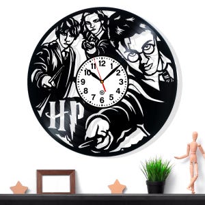 May include: Black vinyl record clock featuring Harry Potter characters. The clock face includes a white clock dial with black numbers and hands. The letters "HP" are visible on the clock.