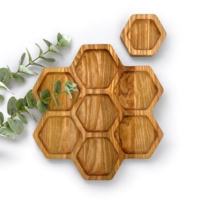Può includere: Un vassoio in legno a forma di favo con otto scomparti. Il vassoio è realizzato in legno marrone chiaro e ha una finitura naturale.