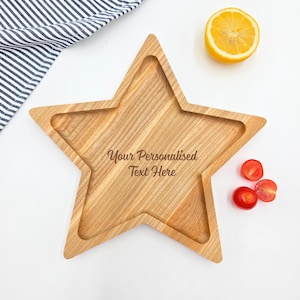 May include: A wooden star-shaped serving tray with a raised edge. The tray is made of light brown wood and has a natural wood finish. The text "Your Personalised Text Here" is engraved on the tray.