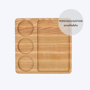 May include: A light-colored wooden serving tray with three circular cutouts and a rectangular section. The text "PERSONALISATION available" is in a white circle in the upper right corner. The tray is made of wood.