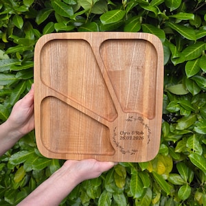 May include: A square wooden serving tray with three compartments and a curved edge. The tray is light brown with a natural wood grain. The text "Chris & Rob 26.03.2026" is engraved in a floral wreath on the tray.