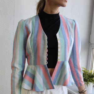 May include: A striped cropped jacket with a peplum hem. The jacket is in shades of pink, blue, and green. The jacket has a V-neck and a button closure.