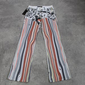 Könnte beinhalten: Weiße, schwarze, orange und cremefarbene, gestreifte Schlaghose mit einem Blumendruck am Bund.