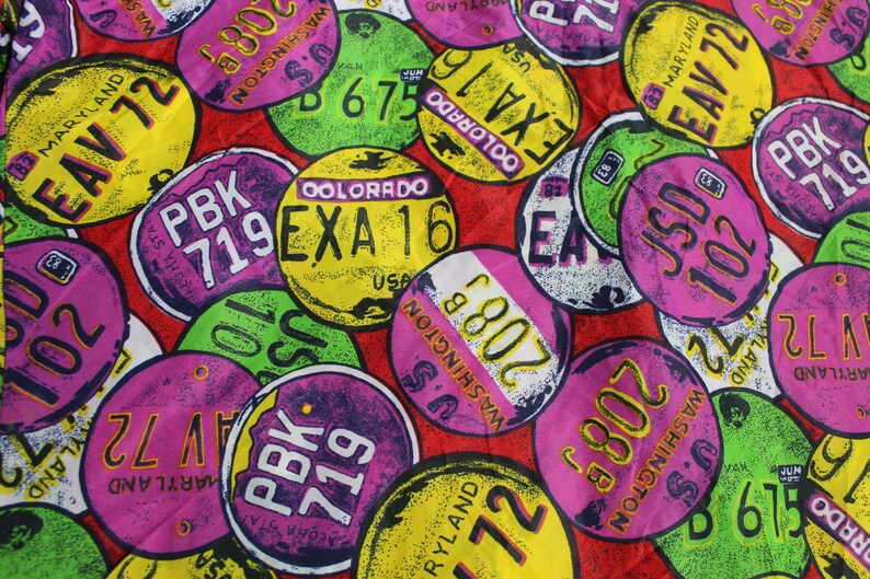May include: A colorful fabric pattern featuring various license plates with different state names and abbreviations, including Maryland, Colorado, Washington, and New York. The plates are in various colors, including pink, green, yellow, and blue.