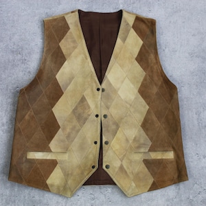 Może przedstawiać: Vintage zamszowa kamizelka w kolorze brązowym z geometrycznym wzorem w romby. Kamizelka posiada dekolt w kształcie litery V, zapięcie na guziki i dwie przednie kieszenie. Paleta kolorów obejmuje odcienie brązu i beżu.