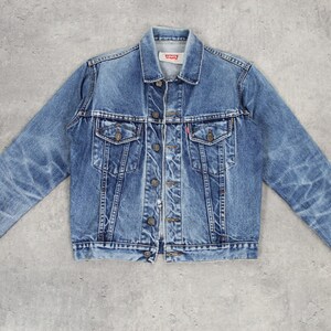 Könnte beinhalten: Eine hellblaue Jeansjacke mit Knopfleiste, zwei Brusttaschen und zwei Fronttaschen. Die Jacke hat einen ausgewaschenen Look und ist aus einem weichen, bequemen Material gefertigt.