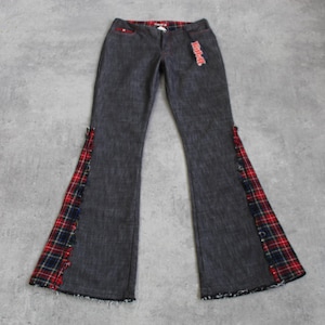 May include: Dark gray flared jeans with red and black plaid accents on the sides. The jeans have a frayed hem and a red plaid detail on the waistband. A tag is attached to the jeans.