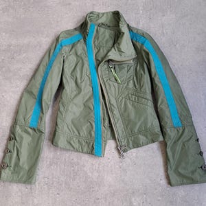 May include: An olive green jacket with a stand-up collar and a full-length zip. The jacket has bright blue stripes down the sleeves and along the zip. The sleeves have button details at the cuffs. A small pocket is on the chest.