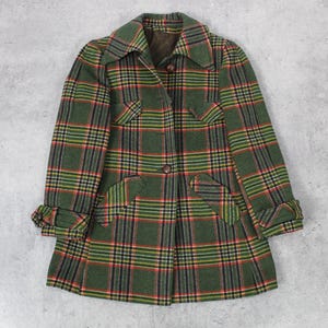 May include: A green, red, and yellow plaid jacket with a button-up front and long sleeves. The jacket has two flap pockets on the front and a collar.