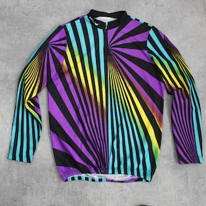Op de afbeelding: Een lang mouw fietsshirt met een kleurrijk, geometrisch patroon van strepen in tinten van paars, blauw, geel en zwart.