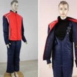 Puede incluir: Un traje de esquí rojo y azul con una franja blanca a lo largo del lado de la chaqueta. La chaqueta tiene una cremallera y una capucha. Los pantalones tienen una cremallera y son de longitud completa.