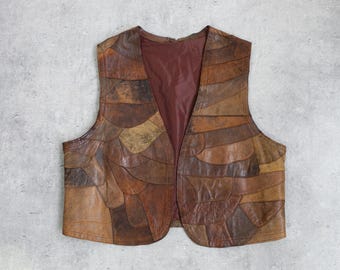 May include: A vintage brown leather vest with a patchwork design. The vest features a variety of brown tones and textures, with a burgundy lining. The vest is open-fronted and appears to be unworn. A unique piece of vintage apparel.