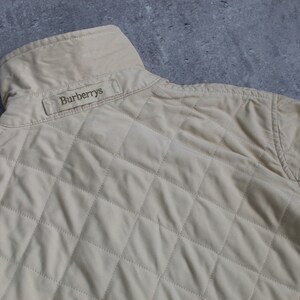 May include: A beige quilted jacket with a Burberrys label on the back.