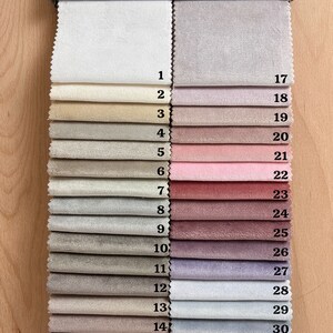 May include: A fabric swatch book with 32 different fabric samples. The swatches are arranged in two columns, with numbers 1-16 on the left and 17-32 on the right. The fabrics range in color from white to gray to pink to purple.