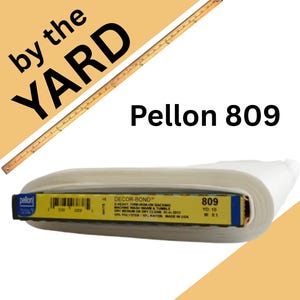 May include: A roll of white Pellon 809 Decor-Bond iron-on backing fabric. The label specifies 90% polyester and 10% rayon, with a length of 10 yards. A wooden yardstick is positioned diagonally above the roll, and the text reads by the YARD.