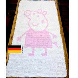 Puede incluir: Una manta de crochet blanca con un diseño de Peppa Pig rosa.