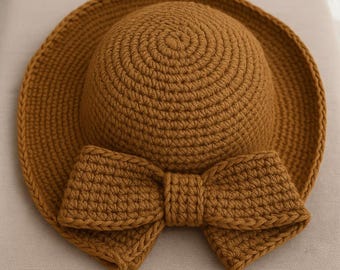 May include: A brown crocheted sun hat with a large brown crocheted bow.