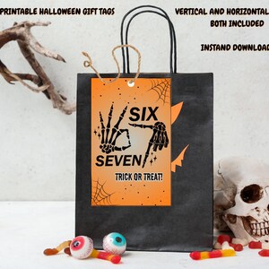 May include: A black gift bag with a Halloween-themed tag that reads "SIX SEVEN TRICK OR TREAT!" in black text on an orange background. The tag features skeleton hands and spiderwebs. The bag also has the text "PRINTABLE HALLOWEEN GIFT TAGS" and "VERTICAL AND HORIZONTAL OPTIONS BOTH INCLUDED INSTAND DOWNLOAD".