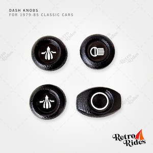 Könnte beinhalten: Vier schwarze Armaturenbrett-Knöpfe mit weißen Markierungen für klassische Autos. Die Knöpfe sind für Fahrzeuge von 1979 bis 1985.