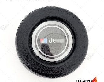 May include: Black round horn button with a silver trim and a clear plastic cover. The button has a Jeep logo with the text "Jeep" inside the cover.
