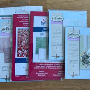 May include: A collection of six Spellbinders embossing folders in clear plastic packaging. The folders feature various designs including Peppermint Stripes, Bricks and Bark, floral patterns, geometric quilt motifs, overlapping circles, and Best Friends.