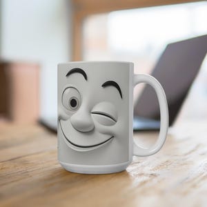 May include: A white ceramic mug featuring a winking face design. The face has a smiling mouth, a winking eye, and curved eyebrows. The mug has a curved handle and is sitting on a wooden surface.