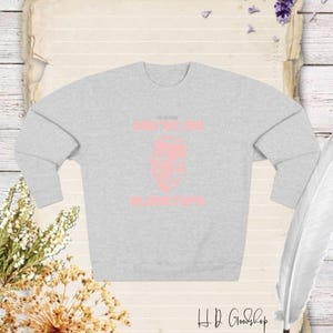 Może przedstawiać: Jasnoszara bluza z napisem "DO YOU KNOW WHAT YOU ARE? BLANKET LIFE" w kolorze różowym. Bluza posiada różową grafikę twarzy. Logo HD Goodshop znajduje się w prawym dolnym rogu.