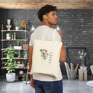 Puede incluir: Una bolsa de tela beige con un diseño floral y el texto "Let us rejoice today and be glad".
