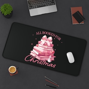 May include: Black mouse pad with a pink and white stack of books decorated with a bow and a snowman. The text "All Booked for Christmas" is written in pink.