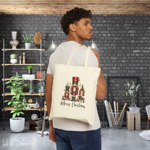 May include: A beige tote bag with a Christmas design featuring a nutcracker and the text "Merry Christmas".