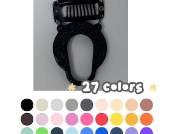 May include: A black glittery hair extension clip with a U-shaped frame and a metal comb attachment. Below the clip, the text 27 colors is displayed alongside a grid of 27 distinct circular color swatches in various shades.