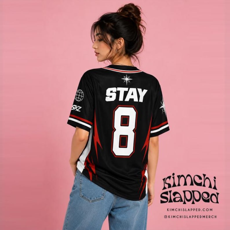 May include: A black short-sleeved jersey featuring the word STAY and the number 8 in white with red outlines on the back. The design includes white star icons, a globe graphic, the text SKZ, and red lightning bolt patterns on the sides and sleeves.