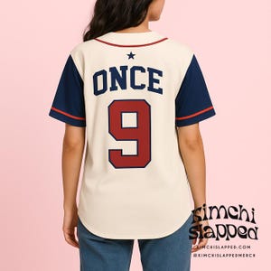 May include: Cream-colored baseball jersey with navy blue sleeves and red trim. The back features the word "ONCE" above the number "9" in navy blue with a red outline. A black star is above the word "ONCE". The jersey has a rounded hem.