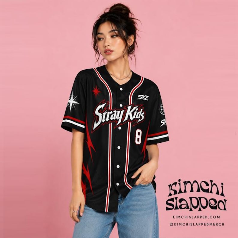May include: A black short-sleeved button-down baseball jersey featuring the text Stray Kids in white with red lightning bolt graphics on the sides. The shirt includes the number 8, a star icon, and the letters SKZ printed in white on the front.