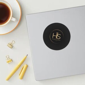 May include: A black and gold round sticker with the letters "HS" in a gold crown. The text "HOMEMADE SWEETS" is below the letters.