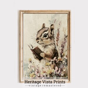 May include: A watercolor illustration of a brown and white chipmunk reading a book. The chipmunk is sitting in a field of pink and purple flowers. The image is framed in a light brown frame with the text "Heritage Vista Prints - vintage remastered -" at the bottom.