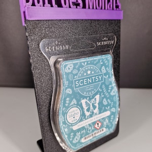 Könnte beinhalten: Ein blauer Scentsy-Wachsschmelzer mit einem Schmetterlingsdesign und dem Text "Blue Lavender & Bergamot" auf der Vorderseite. Der Schmelzer wird in Idaho, USA hergestellt und ist 94 ml / 74 g groß.