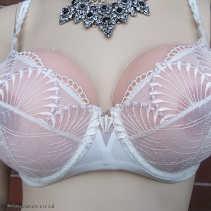 May include: White lace bra with delicate floral embroidery and a sheer mesh design. The bra has a smooth, seamless cup and adjustable straps.
