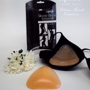May include: Softleaves Bikini X200 silicone breast enhancers in a black retail box. The set includes a pair of nude-colored, triangular silicone inserts and a black fabric bra. The packaging features the text Softleaves and Silicone Breast Enhancers.