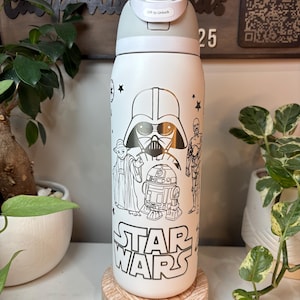 May include: White Star Wars water bottle with black character illustrations, including Darth Vader, Yoda, and R2-D2. The bottle has a gray lid with a 'Lift to Unlock' feature. The Star Wars logo is prominently displayed.